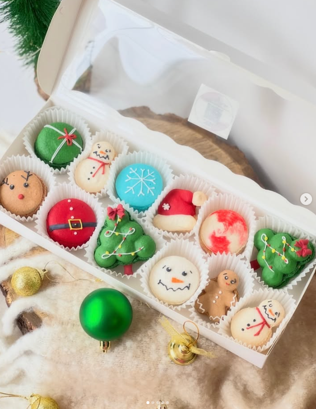 Custom Christmas-themed macarons shaped like snowmen, reindeer, Santa hats, gingerbread men, and trees, etc.