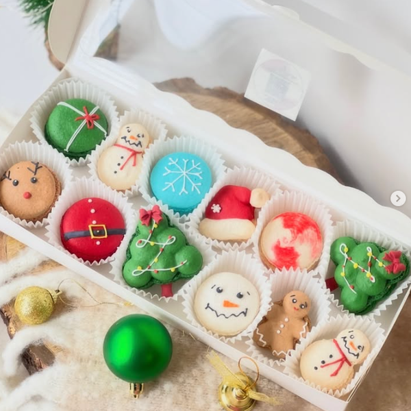 Custom Christmas-themed macarons shaped like snowmen, reindeer, Santa hats, gingerbread men, and trees, etc.